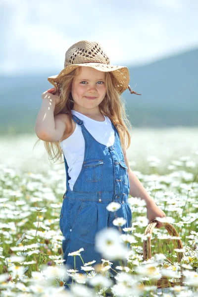 Klein meisje in een veld van bloemen. Het kind heeft plezier in de natuur. — Stockfoto