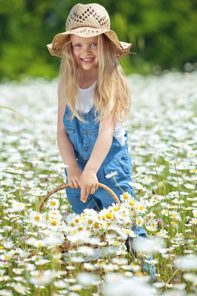 Klein meisje in een veld van bloemen. Het kind heeft plezier in de natuur. — Stockfoto