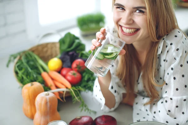 Kvinna på diet. Ung och glad kvinna äter hälsosam sallad sitter på bordet med gröna färska ingredienser inomhus — Stockfoto