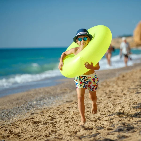 Modischer Junge, Kind spielt in Wellen am Sommerstrand. — Stockfoto