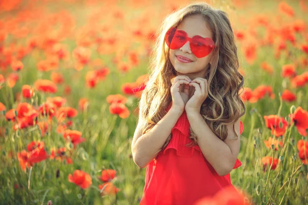 Hermosa niña en un campo de amapolas, retrato al aire libre. Niño en un campo con flores. — Foto de Stock