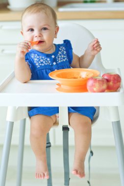 Yüksek sandalyedeki küçük bir çocuk karnını doyuruyor.. 