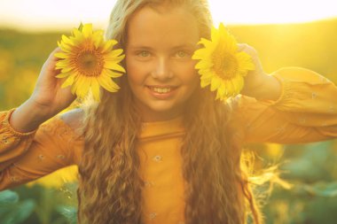 Ayçiçekli güzel kız doğanın tadını çıkarıyor ve yaz ayçiçeği tarlasında gülüyor. Güneş parlıyor, güneş ışıldıyor, güneş parlıyor..