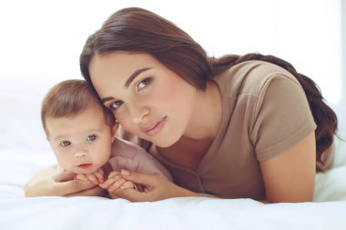 Genç bir anne yeni doğmuş bebeğini kucağında tutuyor. Emziren bir bebeğin annesi. Anne bebeğini emziriyor. Aile evdedir. Mutlu bir anne ve çocuğun portresi..