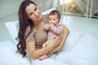 Genç bir anne yeni doğmuş bebeğini kucağında tutuyor. Emziren bir bebeğin annesi. Anne bebeğini emziriyor. Aile evdedir. Mutlu bir anne ve çocuğun portresi..