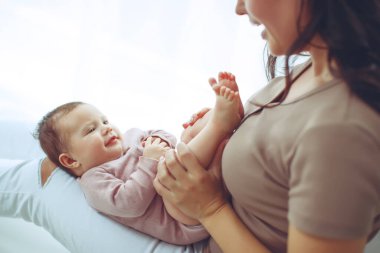 Genç bir anne yeni doğmuş bebeğini kucağında tutuyor. Emziren bir bebeğin annesi. Anne bebeğini emziriyor. Aile evdedir. Mutlu bir anne ve çocuğun portresi..