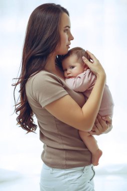 Genç bir anne yeni doğmuş bebeğini kucağında tutuyor. Emziren bir bebeğin annesi. Anne bebeğini emziriyor. Aile evdedir. Mutlu bir anne ve çocuğun portresi..