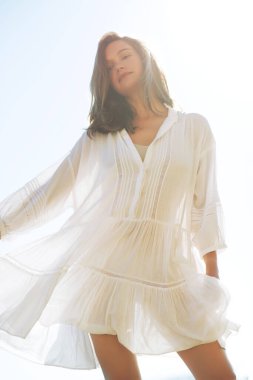 Hafif elbiseli bir kadın, güzel dalgalı saçlar, yumuşak günbatımı ışığı.