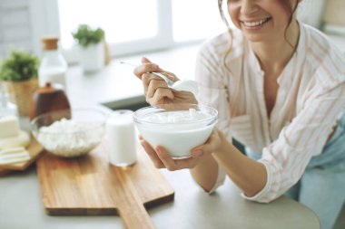 Sütlü genç bir kadın, süzme peynir, ekşi krema, evde mutfaktaki peynir, masada oturan güzel bir kız, mutlu bir kadın gülümsemesi, doğal organik bir gülümseme..