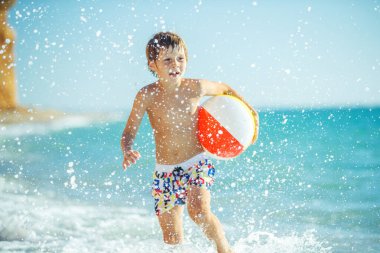 Çocuk denizde eğleniyor. Yaz, mutluluk, deniz ve çocuklu bir top.. 