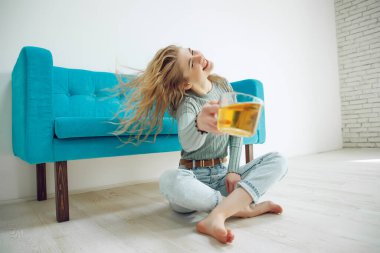 Genç bir kadın evde oturuyor ve çay içiyor..