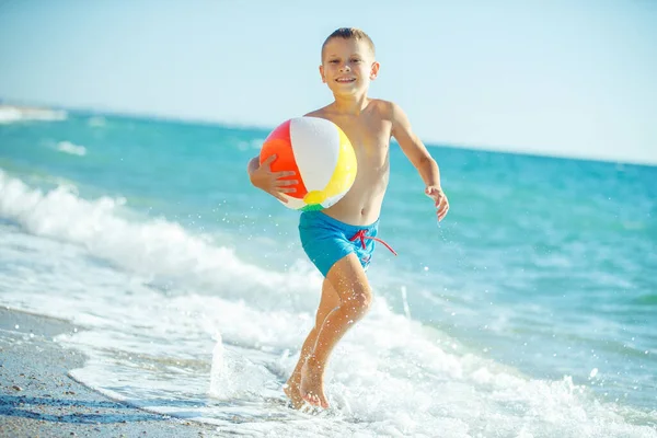Junge Kind hat Spaß auf See. Sommer, Glück, Meer und ein Kind mit Ball. — Stockfoto