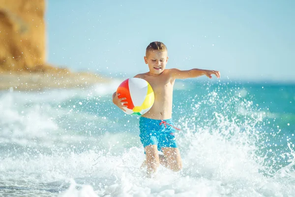 Junge Kind hat Spaß auf See. Sommer, Glück, Meer und ein Kind mit Ball. — Stockfoto