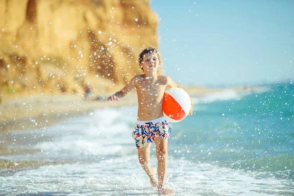 Junge Kind hat Spaß auf See. Sommer, Glück, Meer und ein Kind mit Ball. — Stockfoto