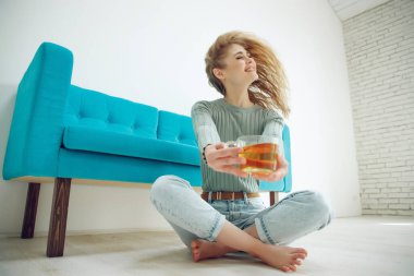 Genç bir kadın evde oturuyor ve çay içiyor..