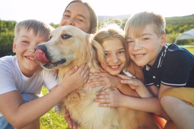 Çocuklar doğada köpekle oynarlar..