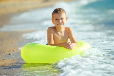 Çocuk denizde eğleniyor. Yaz, mutluluk, deniz ve çocuklu bir top.. 