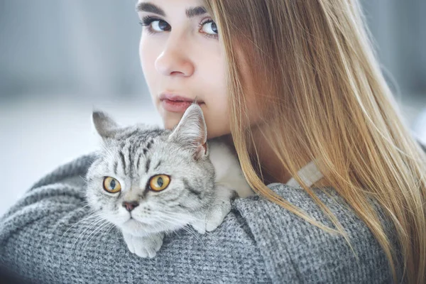 Hermosa joven con un lindo gato está descansando en casa. — Foto de Stock