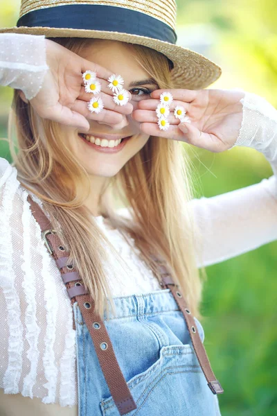 Mooie mooie stijlvolle vrouw met strohoed, mooie kamillebloem, romantische stemming, poseren in de natuur, rusten in een zomerpark, natuurlijke uitstraling. — Stockfoto