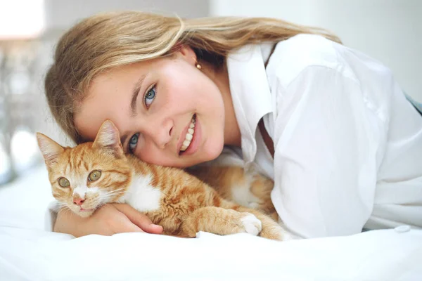 Девушка отдыхает на кровати со своим рыжим котенком. Ребенок с животным. — стоковое фото