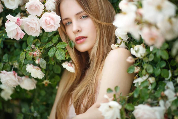 Bella giovane donna odora un fiore di rosa — Foto Stock