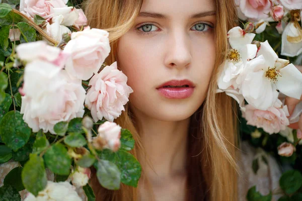 Güzel genç kadın bir gül çiçeği kokusu alıyor. — Stok fotoğraf