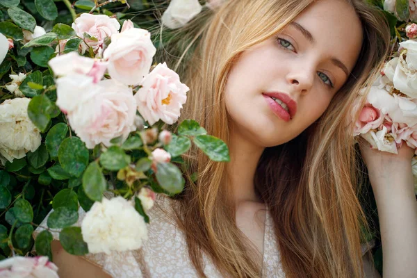 Kaunis nuori nainen haisee ruusun kukka — kuvapankkivalokuva
