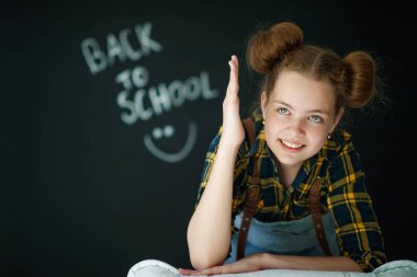 Mutlu gülümseyen kız. Tahtadaki çocuk. Arka planda yazı tahtası olan kapalı alan sınıfındaki kız. Okula dönüyoruz..
