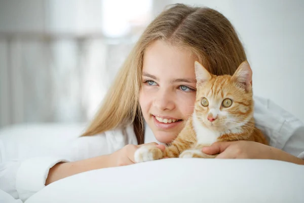 Chica con un gato. Un niño con una mascota en casa. — Foto de Stock