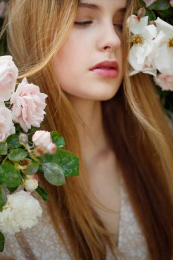 Güzel genç kadın bir gül çiçeği kokusu alıyor.