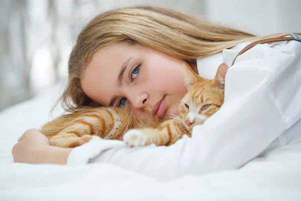 Chica con un gato. Un niño con una mascota en casa. — Foto de Stock