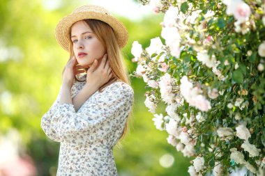 Güzel genç kadın bir gül çiçeği kokusu alıyor.