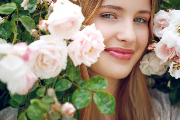 Mooie jonge vrouw ruikt een roos bloem — Stockfoto