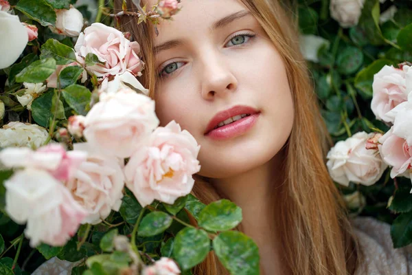 Güzel genç kadın bir gül çiçeği kokusu alıyor. — Stok fotoğraf