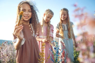 Çocuklar doğada boyayla resim yaparlar.