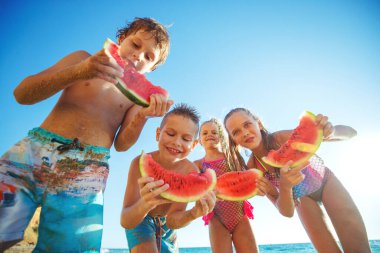 Denizde karpuzlu çocuklar. Bir grup çocuk denizde oynarken eğleniyor..