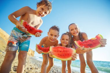 Denizde karpuzlu çocuklar. Bir grup çocuk denizde oynarken eğleniyor..