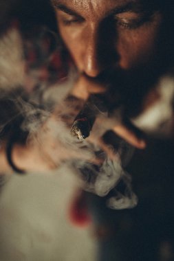 Adam sigara içiyor. Genç bir adam puro içiyor..