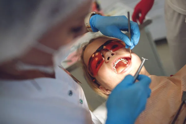 Дівчинка-підліток з брекетами, яка відвідує ортодонта в клініці. Монтаж брекет-системи . — стокове фото