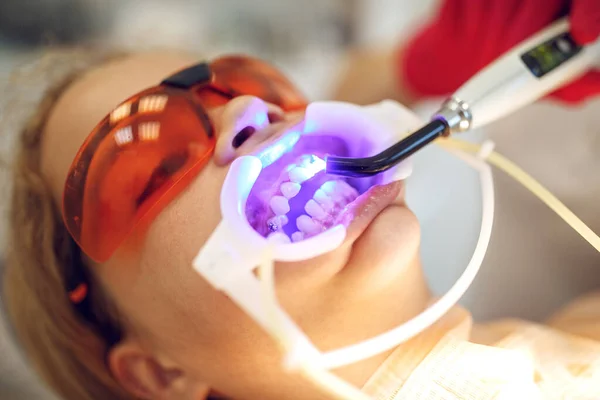Tienermeisje met beugel op bezoek bij de orthodontist in de kliniek. Installatie van een beugelsysteem. — Stockfoto