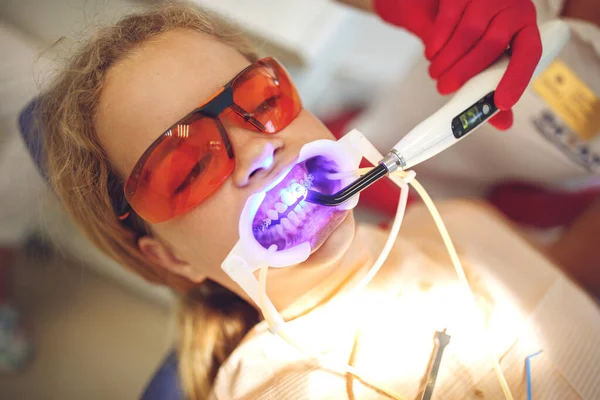 Adolescente con aparatos ortopédicos visitando al ortodoncista en la clínica. Instalación del sistema de frenado. — Foto de Stock