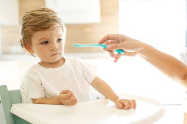 Annesi bebeği besliyor. Genç bir kadın bebeğini kaşıkla besliyor..