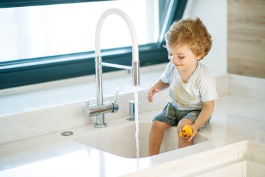 Çocuk ellerini yıkar. Küçük çocuk musluk suyuyla oynuyor..