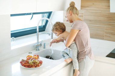 Çocuk ellerini yıkar. Annem küçük bir çocuğun ellerini yıkamasına yardım eder..