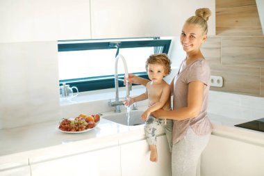 Çocuk ellerini yıkar. Annem küçük bir çocuğun ellerini yıkamasına yardım eder..