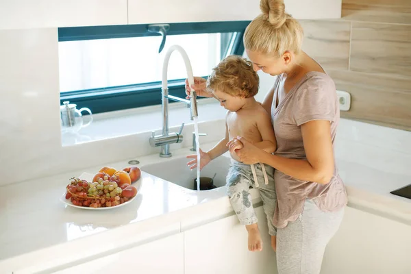 Дитина миє руки. Мама допомагає маленькому хлопчику помити руки . — стокове фото