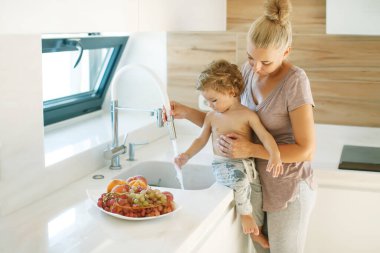 Çocuk ellerini yıkar. Annem küçük bir çocuğun ellerini yıkamasına yardım eder..