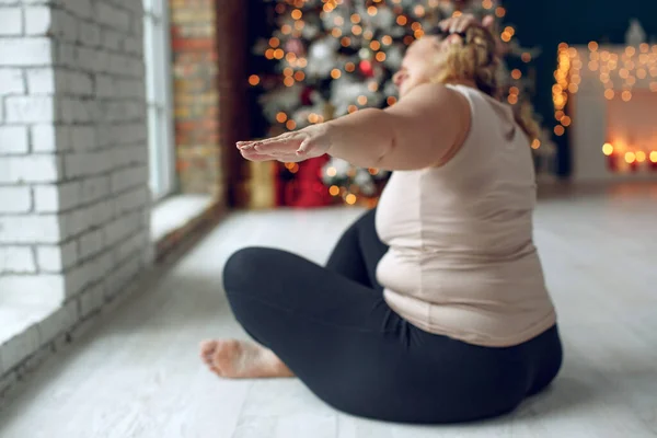 Fet kvinna går in för sport. Yoga vid jul. — Stockfoto