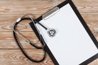 Tıbbi Pano ve ahşap masa arka plan üzerinde stetoskop.