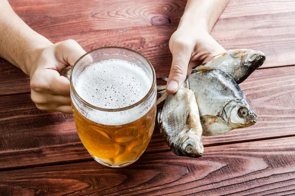 Mano con vaso de cerveza y pescado seco . — Foto de Stock